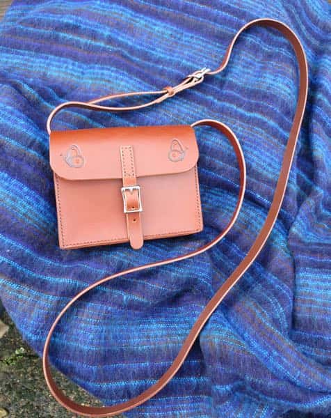 Small brown leather shoulder bag showing strap. Butterfly motif.