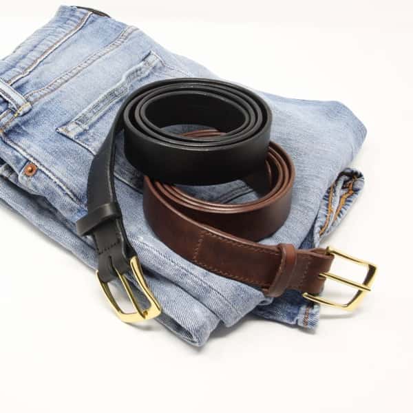 Italian black and brown leather belts with brass buckle shown on a pair of jeans