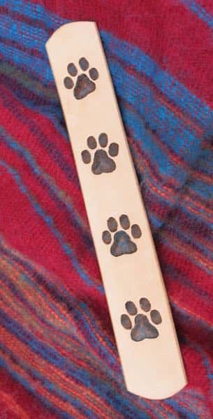 Large paw print motif leather bookmark on red cloth background