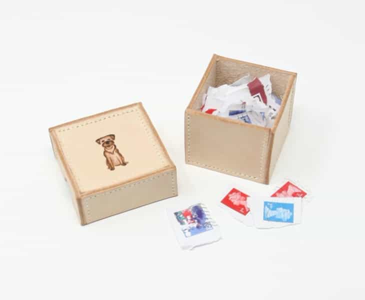 Small square box with border terrier motif, shown containing stamps