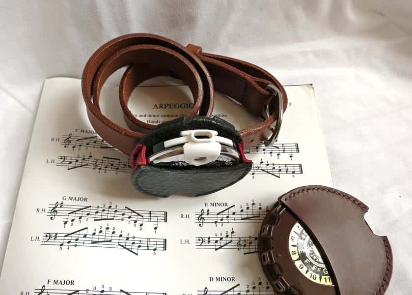 Leather pitch pipe holsters on a sheet music background