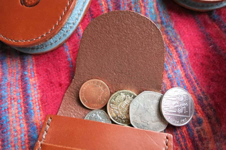 Small brown leather coin pouch open showing money