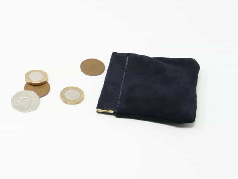 Traditional navy blue suede snap purse shown next to some coins