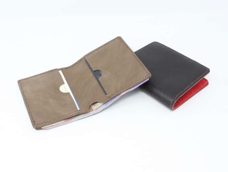 Two slim line leather wallets. One tan inner and the other with a black outer and red inner.