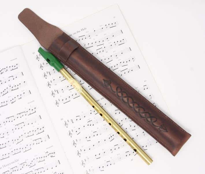 Penny whistle and brown leather penny whistle case on sheet music